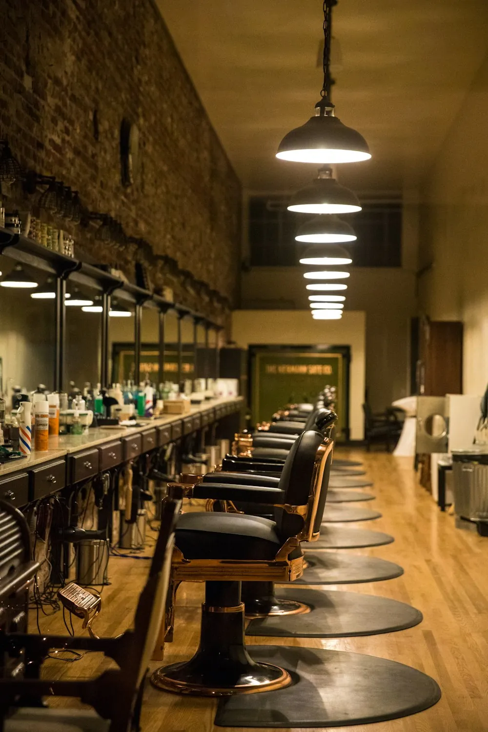 Salão da barbearia com cadeiras enfileiradas e luminárias acesas